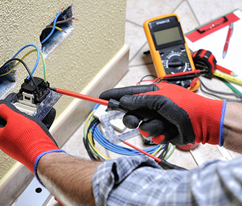 Electrician at work with safety equipment on a residential electrical system.